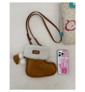 Close-up of brown suede boot-shaped crossbody bag with white faux shearling trim