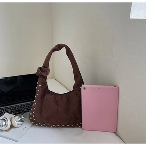 Detail of dark brown suede hobo bag featuring silver rivets and a knotted shoulder strap