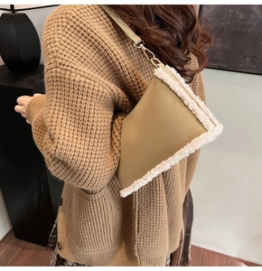 Detail of khaki faux fur shoulder bag worn with brown knit cardigan in soft light