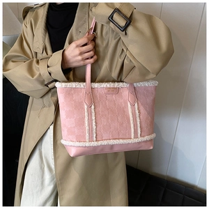 Detail of pink tote bag featuring embossed clover patterns and white faux fur trim finish