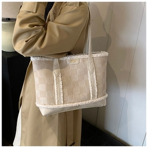 Detail of beige tote bag with white plush trim and wavy embossed texture on model