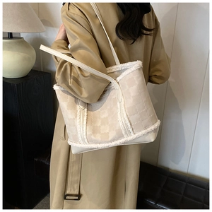 Detail of beige clover embossed tote bag with plush faux fur trim and chic metal hardware
