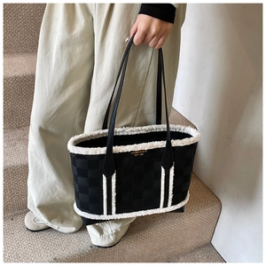 Detail of black tote bag with white plush trim and embossed pattern texture