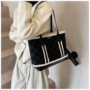 Detail of checkered tote bag with white faux fur trim and metallic logo plaque
