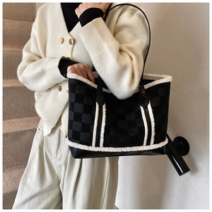 Detail of the black clover pattern tote bag with white faux shearling trim and long handles