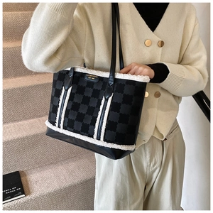 Close-up of black jacquard tote bag with white faux fur trim and metal logo detail