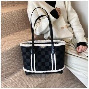 Detail of black contrast tote bag featuring white faux fur trim and branded metal logo