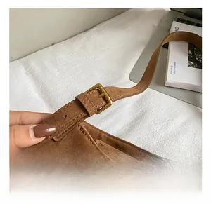 Detailed shot of the golden adjustable metal buckle and embroidered strap on the suede tote bag