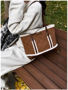 Detailed shot of a brown tote bag with white faux fur trim and embossed pattern on a bench