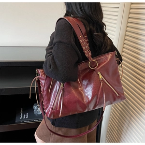 Detail of burgundy tote bag showing braided strap and metallic ring attachment