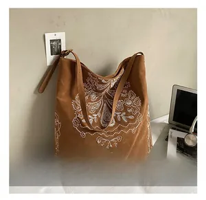 Close-up of vintage brown suede tote bag featuring detailed white floral embroidery