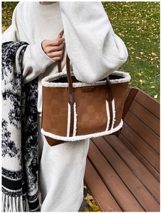 Detail of brown tote bag featuring plush white faux fur trim and premium metal logo plate