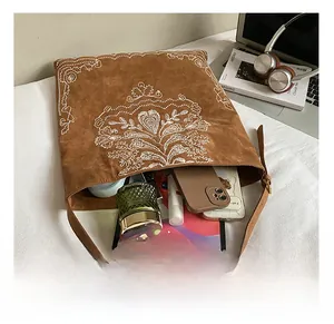 Macro shot of large capacity interior for brown suede tote with ethnic floral embroidery