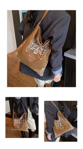 Detail of bohemian embroidery on a brown suede tote bag worn by a model in casual style