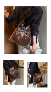 Close-up of vintage brown suede tote bag with intricate white paisley floral embroidery
