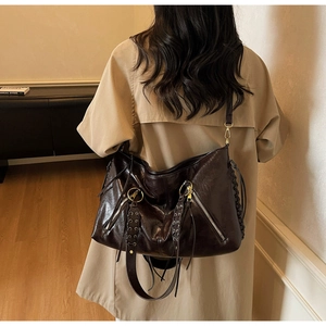 Detail of dark brown leather tote featuring woven lace side and metallic hardware
