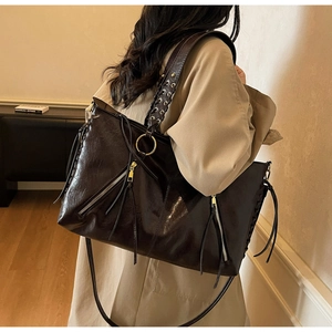 Detail of coffee brown tote bag featuring wax leather texture and braided tassel strap