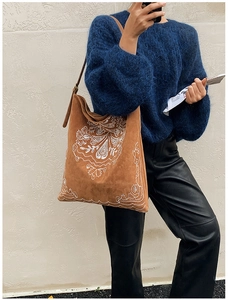 Detailed view of bohemian white embroidery on a brown suede bucket shoulder bag