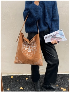 Detail of bohemian embroidery pattern on brown suede tote bag with retro shoulder strap