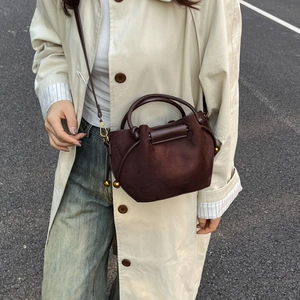 Dark brown suede bucket bag with metallic gold sphere pendant and slim shoulder strap
