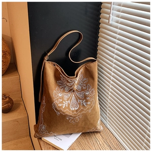 Detailed embroidery and suede texture on a vintage brown bohemian shoulder bag