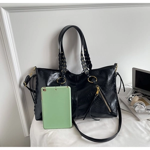 Detail of black faux leather tote bag with gold rings, woven straps and large capacity