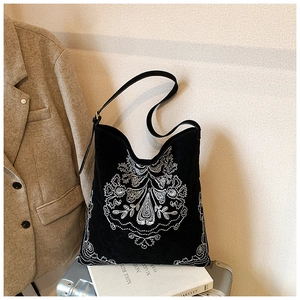 Detail of bohemian black canvas bag with intricate white ethnic embroidery on a suitcase