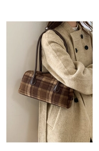 Detail of checkered woolen tote bag on model showing texture and brown leather strap