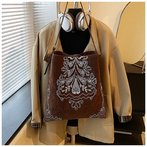 Detail of bohemian dark brown suede bucket bag featuring intricate white floral embroidery