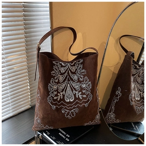 Detailed embroidery on vintage brown suede shoulder bag with adjustable gold buckle strap