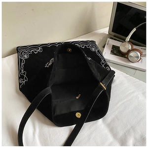 Detail view of black embroidered tote bag with magnetic closure and inner zipper pocket