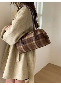 Detail of checkered shoulder bag with brown leather strap and wool texture