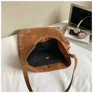 Detail of bohemian suede tote with white embroidery, magnetic clasp and interior pocket