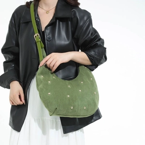Green suede hobo bag with gold studs on a model wearing black leather jacket