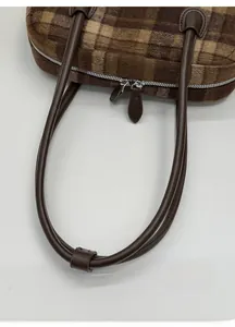 Detail of premium brown plaid plush bag with durable leather straps and metal zipper
