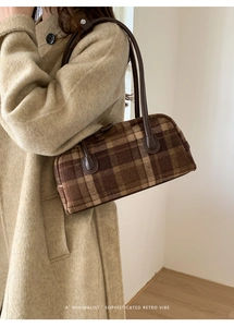 Detail of retro plaid handbag with brown leather handles worn with a beige wool coat