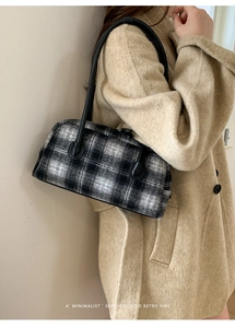 Close-up of black and white houndstooth fabric with premium leather handles on handbag