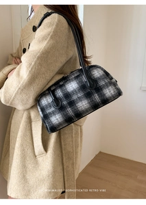 Close-up of black and white plaid handbag with leather handles and metal zipper detail