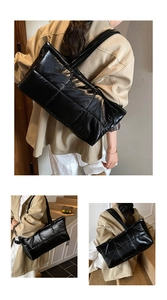 Detailed view of black quilted puffer tote bag with glossy finish on shoulder of a model