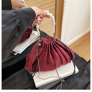 Détail d'un sac seau plissé bordeaux avec anse en perles élégante et cordon de serrage