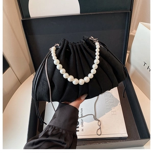 Détail du sac seau noir plissé avec poignée en perles et chaîne dans sa boîte cadeau