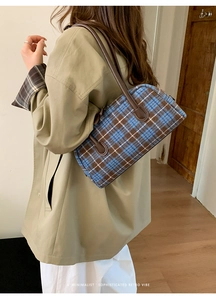 Close-up of retro plaid baguette bag with leather strap on model in a minimalist setting