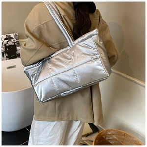 Detailed view of silver quilted tote bag with metallic puffer texture on a model