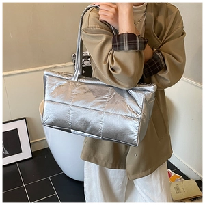 Close-up of quilted silver puffer tote bag showing metallic texture and modern shoulder straps