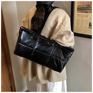 Detail shot of black quilted puffer tote bag with glossy metallic finish and shoulder strap