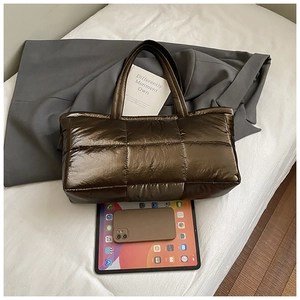 Detailed shot of bronze metallic quilted tote bag with size comparison to tablet