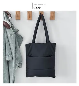 Detail of black quilted nylon tote bag hanging on wooden hook with casual headphones