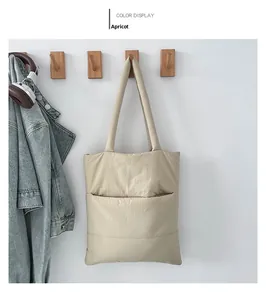 Detail of apricot quilted puffer tote bag hanging on wooden hook with lifestyle props