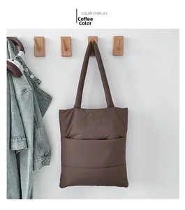 Detailed view of a brown padded quilted tote bag featuring a front pocket and wide strap