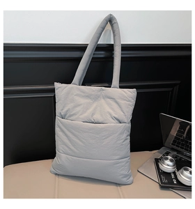 Detailed view of gray quilted tote bag with horizontal padded pockets and shoulder straps